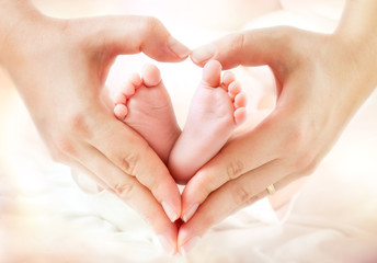 mom hands make heart around newborn feet -