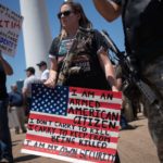 Gun advocates carry firearms and hold signs during open carry firearm rally during NRA meeting in Dallas, Texas