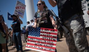 Gun advocates carry firearms and hold signs during open carry firearm rally during NRA meeting in Dallas, Texas