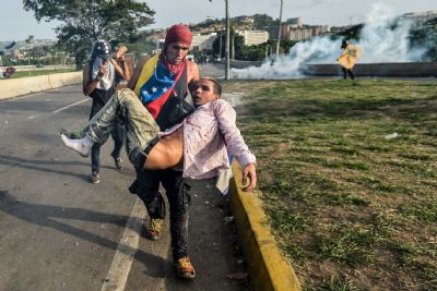 injured demonstrator carried away from protest in Caracas, Venezuela