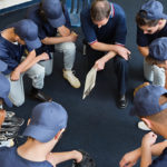 High school baseball players praying together in locker room