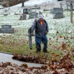 Worker clears leaves in a cemetary