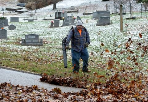 Worker clears leaves in a cemetary