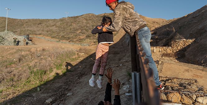 Illegal immigrants lifting child over the wall