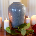 red rose and cremation urn with burning candles