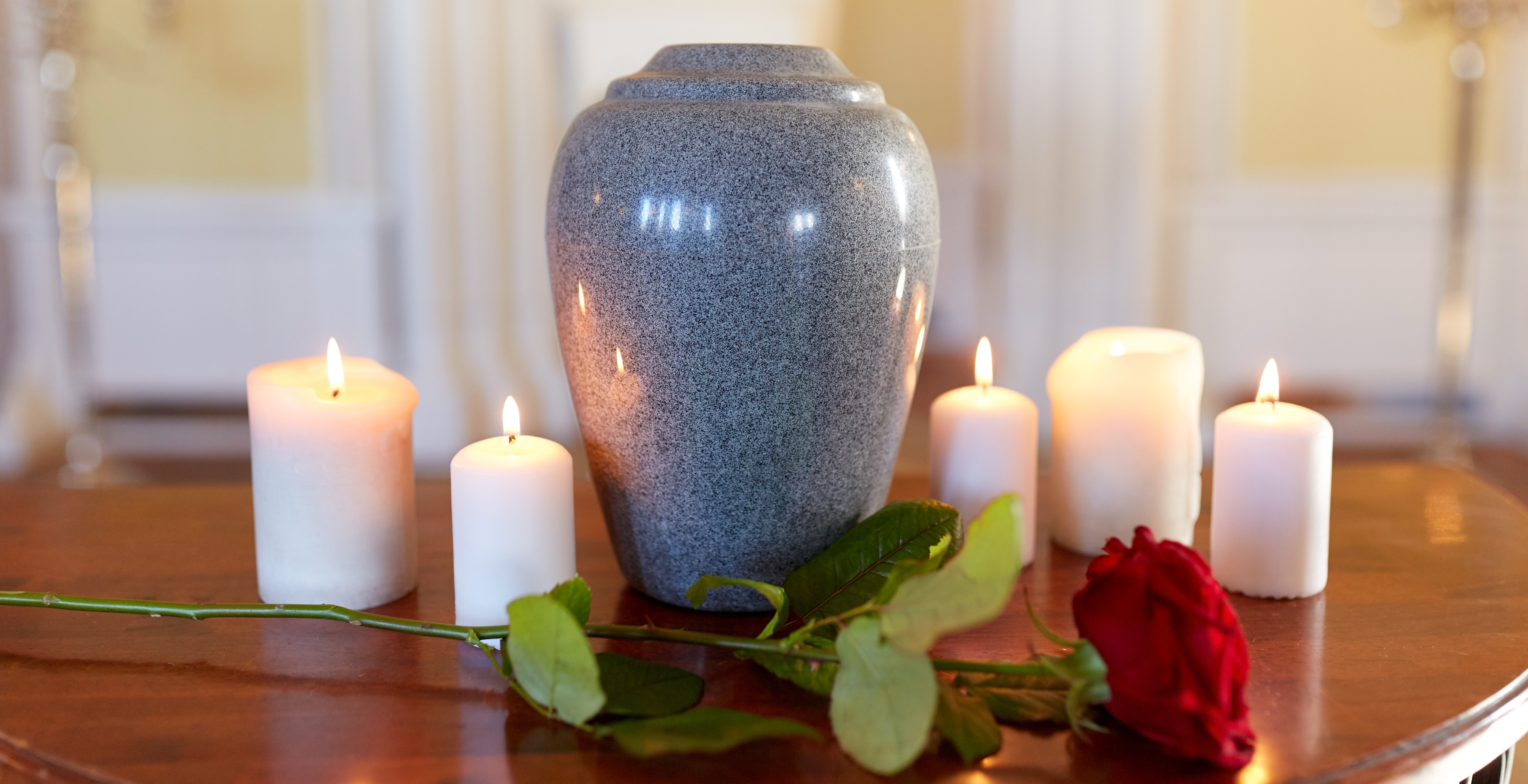 red rose and cremation urn with burning candles