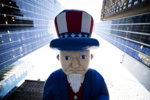 cartoon- sad Uncle Sam in row of office bldgs