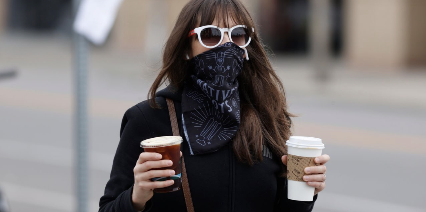 Woman in bandana mask carries 2 coffees