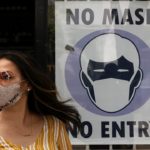 masked woman in front of business