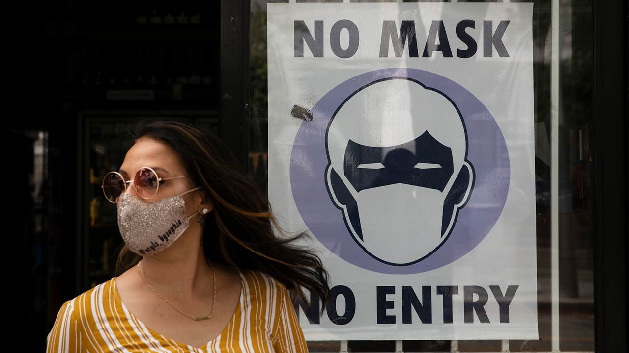 masked woman in front of business