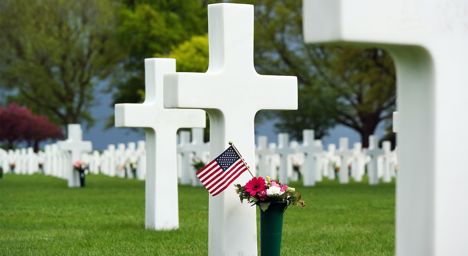 Flowers and a small flag of the US between cross headstones at t