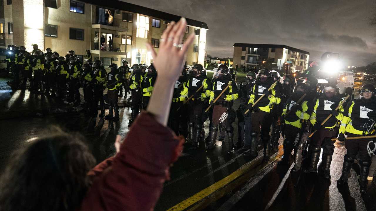 person surrounded by police has hands raised