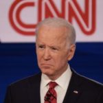 Biden frowns w CNN logo behind him