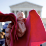 Pro-life protester holds tiny baby doll