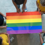 Multi-racials-hold-edges-of-Pride-flag