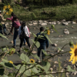 illegal immigrants step on stones to cross Rio Grande