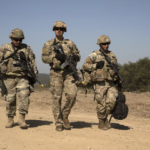US troops walking or patrolling thru arid territory