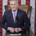 Kevin McCarthy standing at Speakers's desk - buttoning suit