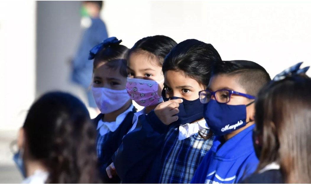 masked grade school children in uniforms