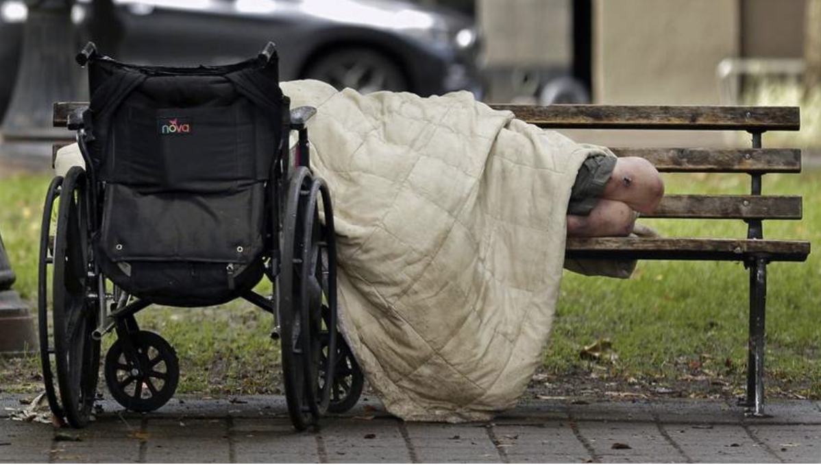 Homeless amputee sleeps on a park bench