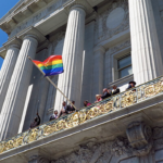 Waving a Pride flag from the balcony of a building