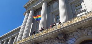 Waving a Pride flag from the balcony of a building