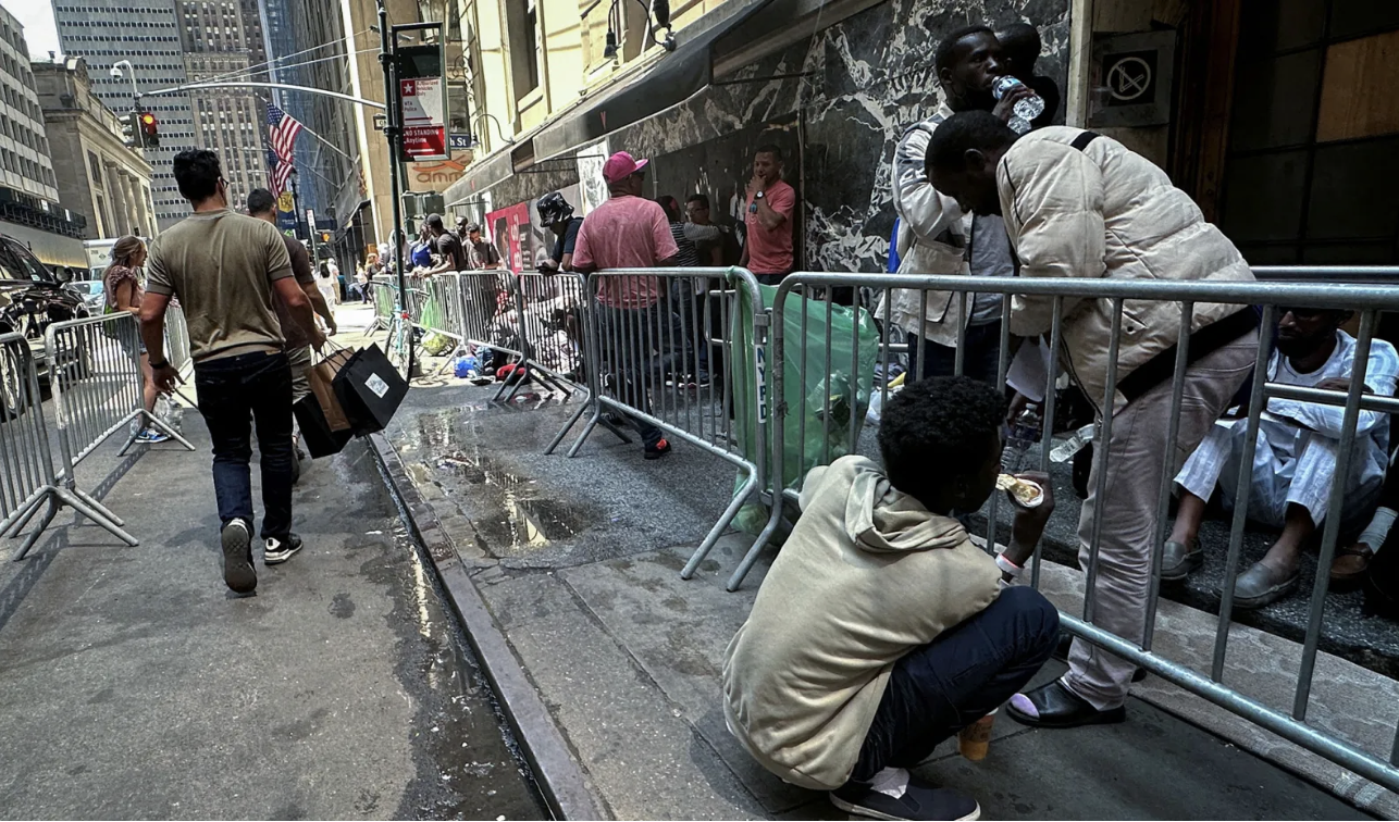 Recently-arrived migrants waiti outside Roosevelt Hotel, midtown Manhattan