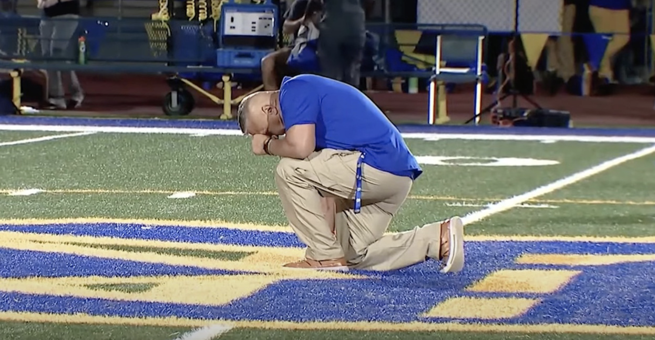 Coach Kennedy kneels after foodball game