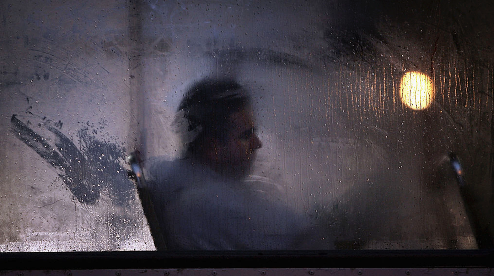 sad Man behind rain streaked glass
