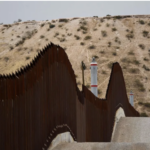 US Border Patrol vehicle sits next to a border wall in the El Paso Sector