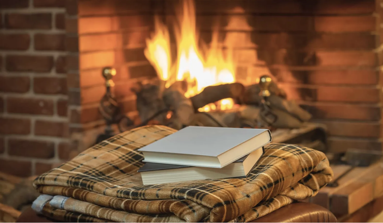 books on a blanket in front of roaring fire place
