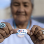 Older hispanic woman holds I voted sticker