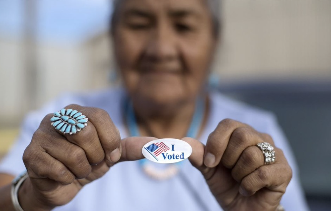 Older hispanic woman holds I voted sticker