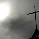 a cross backlit by a cloud covered sun