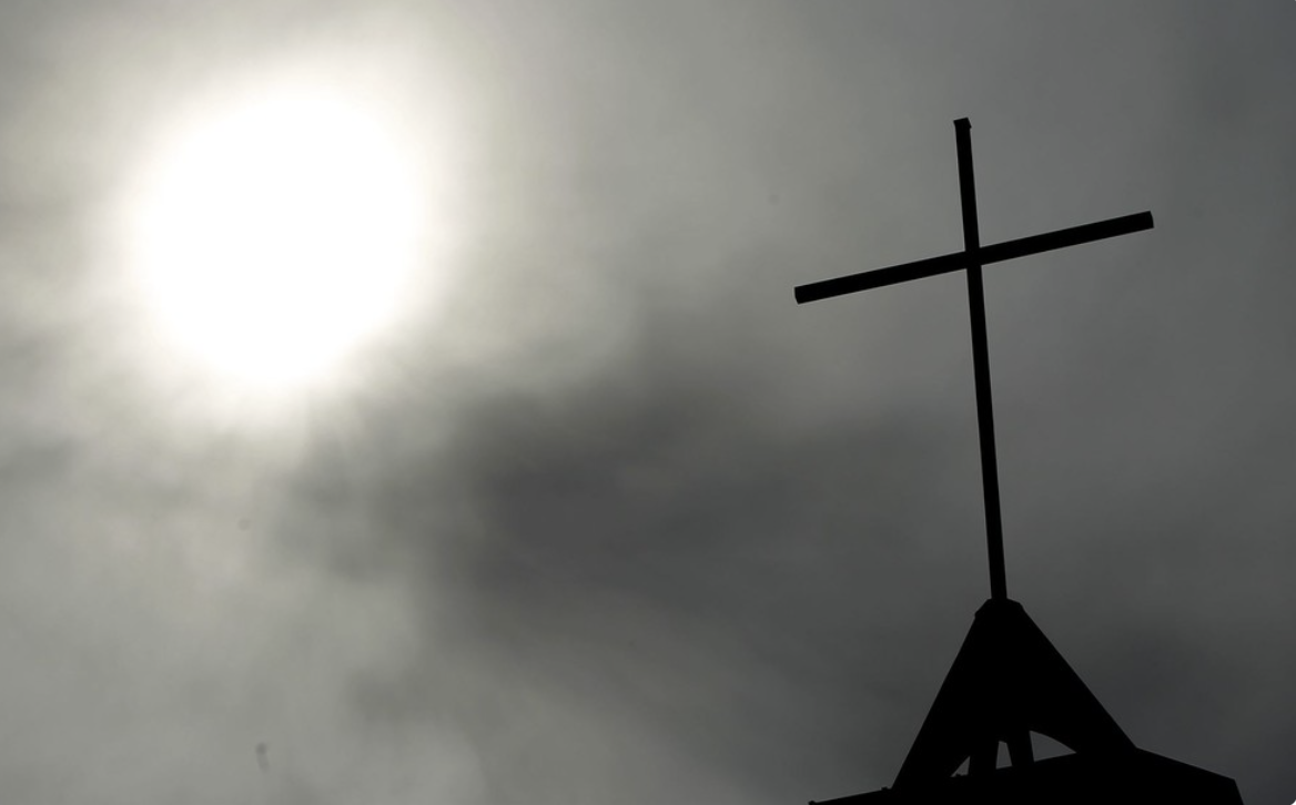 a cross backlit by a cloud covered sun