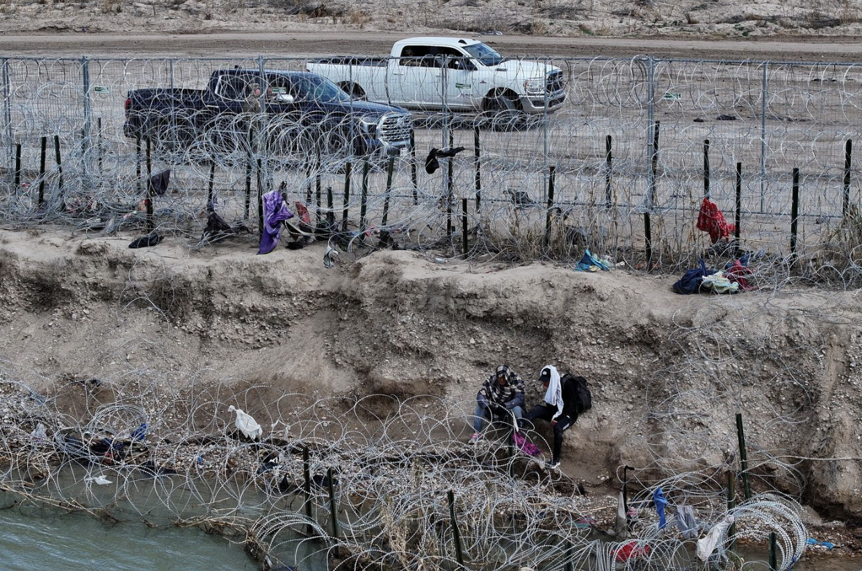 Illegal migrants wait between razor-wire in Eagle Pass, TX