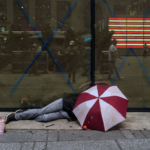 homeless man lies under an umbrella - Times Square NY