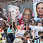 liberal protesters carry signs of conservative Supreme Court Justices