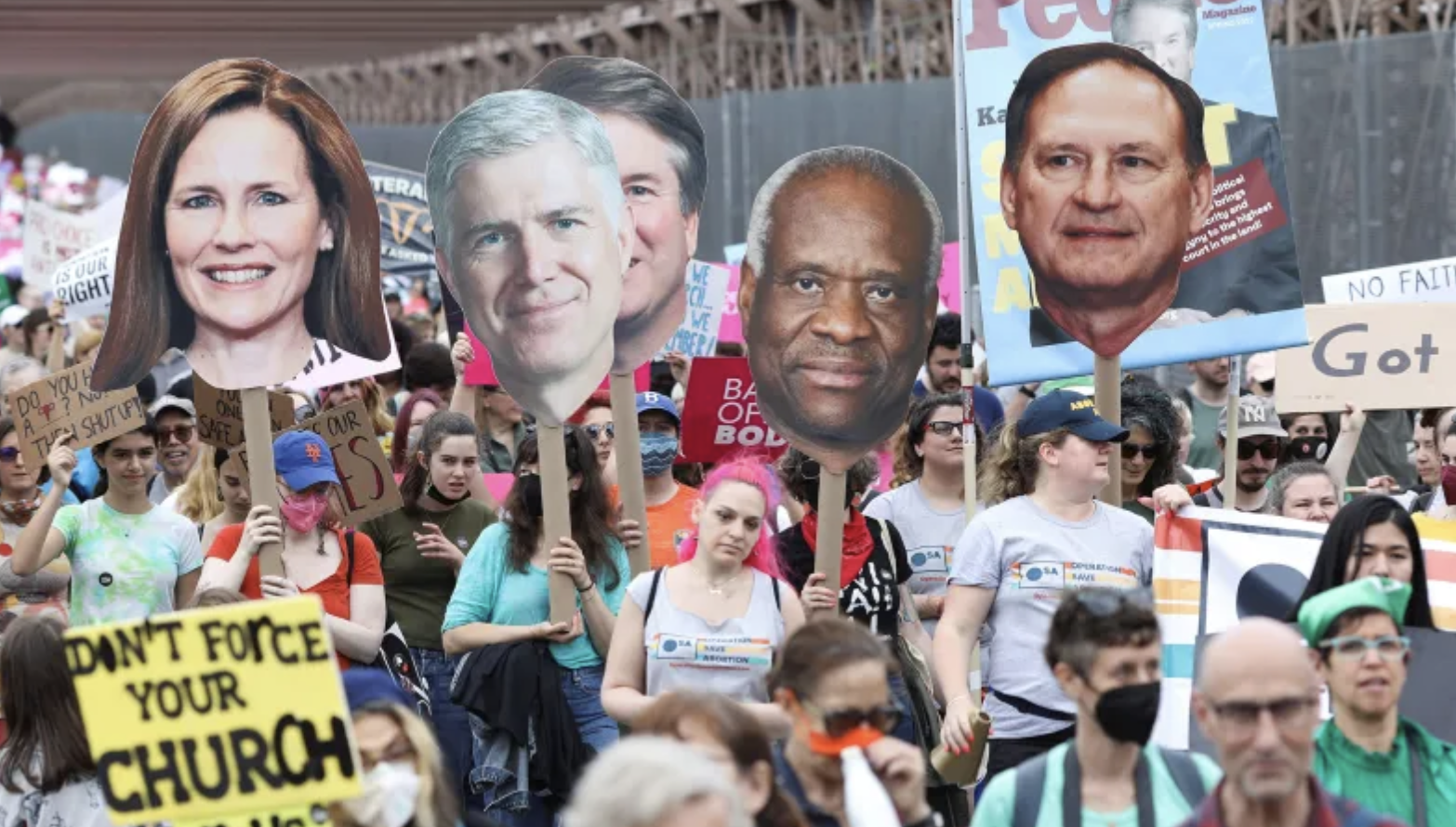 liberal protesters carry signs of conservative Supreme Court Justices