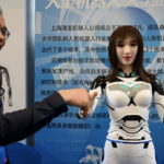 Exhibitor shakes hands with humanoid robot - 2024 China Humanoid Robot Developers Conference - Shanghai