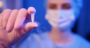 masked hospital worker holds frozen embryo