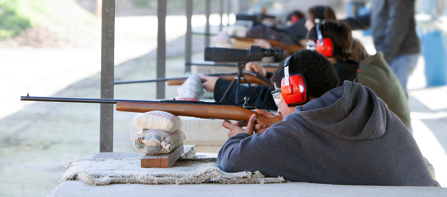 Young men shooting rifles at gun range