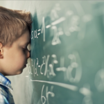 young boy student struggles - head to chalkboard