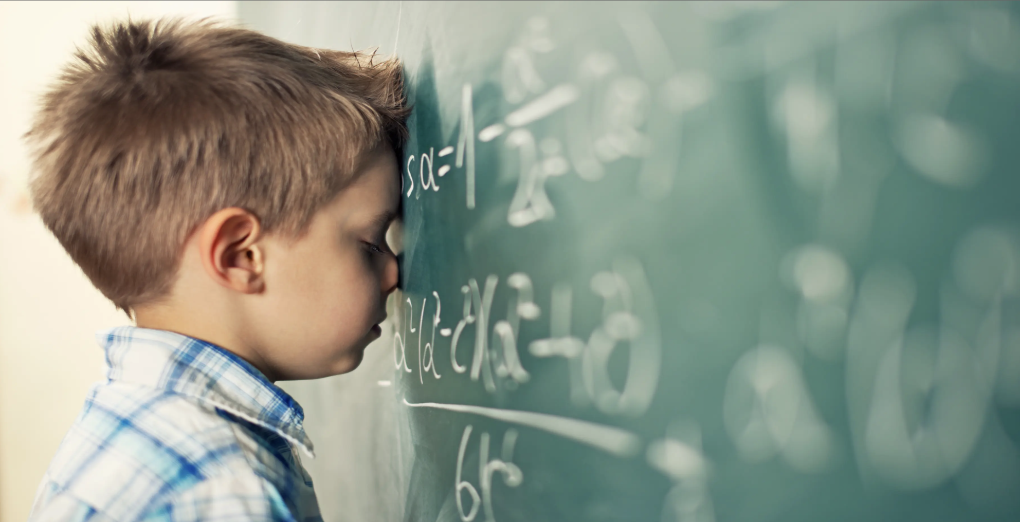 young boy student struggles - head to chalkboard