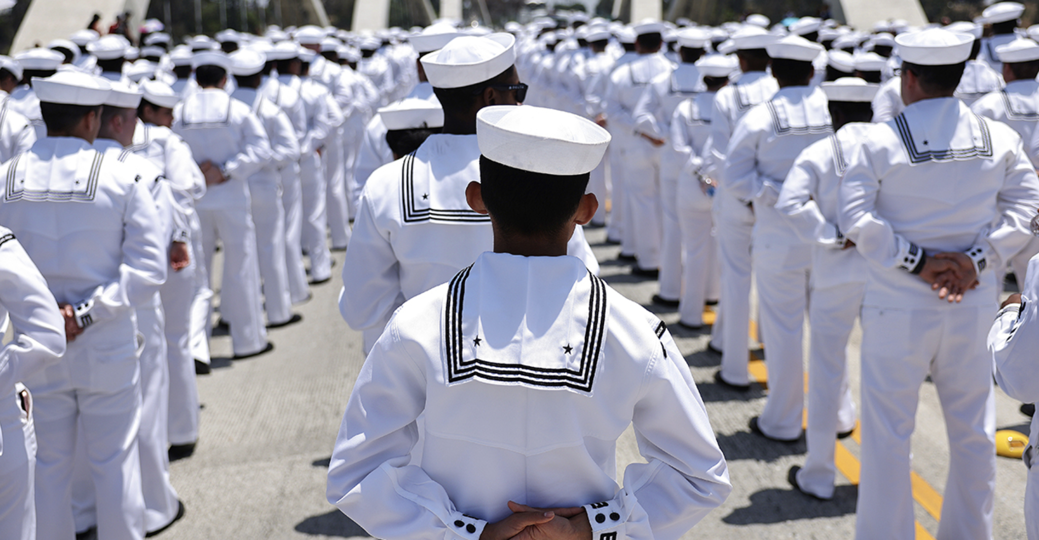 Navy sailors in rows stand at attention on ship deck