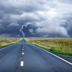 long straight 2-lane road heading into storm Lightening