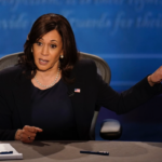 Kamala at table speaks and points