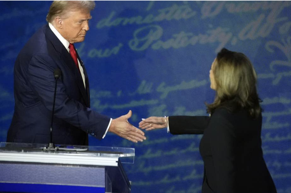 Trump on dias leans down to shake hands with VP Harris