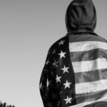 black and white - young person wearing US flag jacket