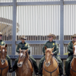 Armed mounted Border Patrol Agents in front of The Wall